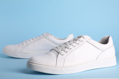 Photo of Pair of stylish white sneakers on light blue background