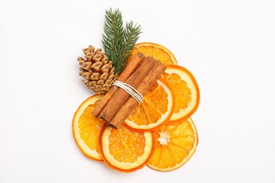 Photo of Dry orange slices, cinnamon sticks, fir branches and cone on white background, top view