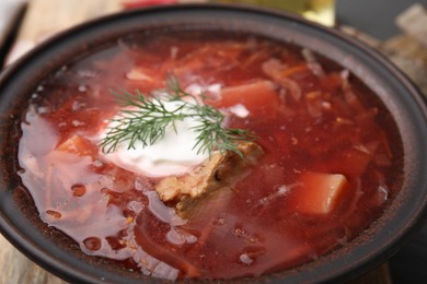 Photo of Tasty borscht with sour cream in bowl on table, closeup