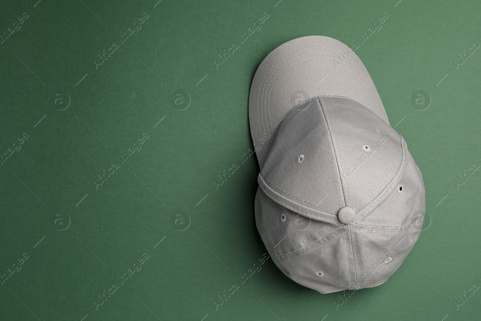 Photo of Stylish grey baseball cap on dark green background, top view. Space for text