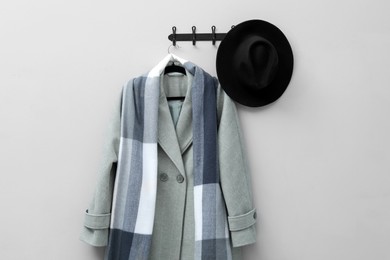 Hanger with coat, scarf and hat on light grey wall