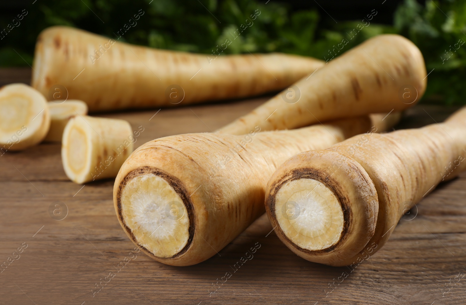 Photo of Fresh ripe parsnips on wooden table, closeup