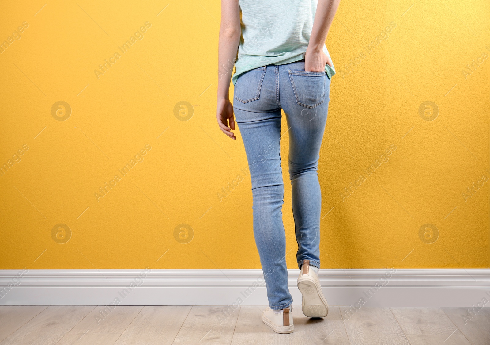 Photo of Young woman in stylish jeans near color wall