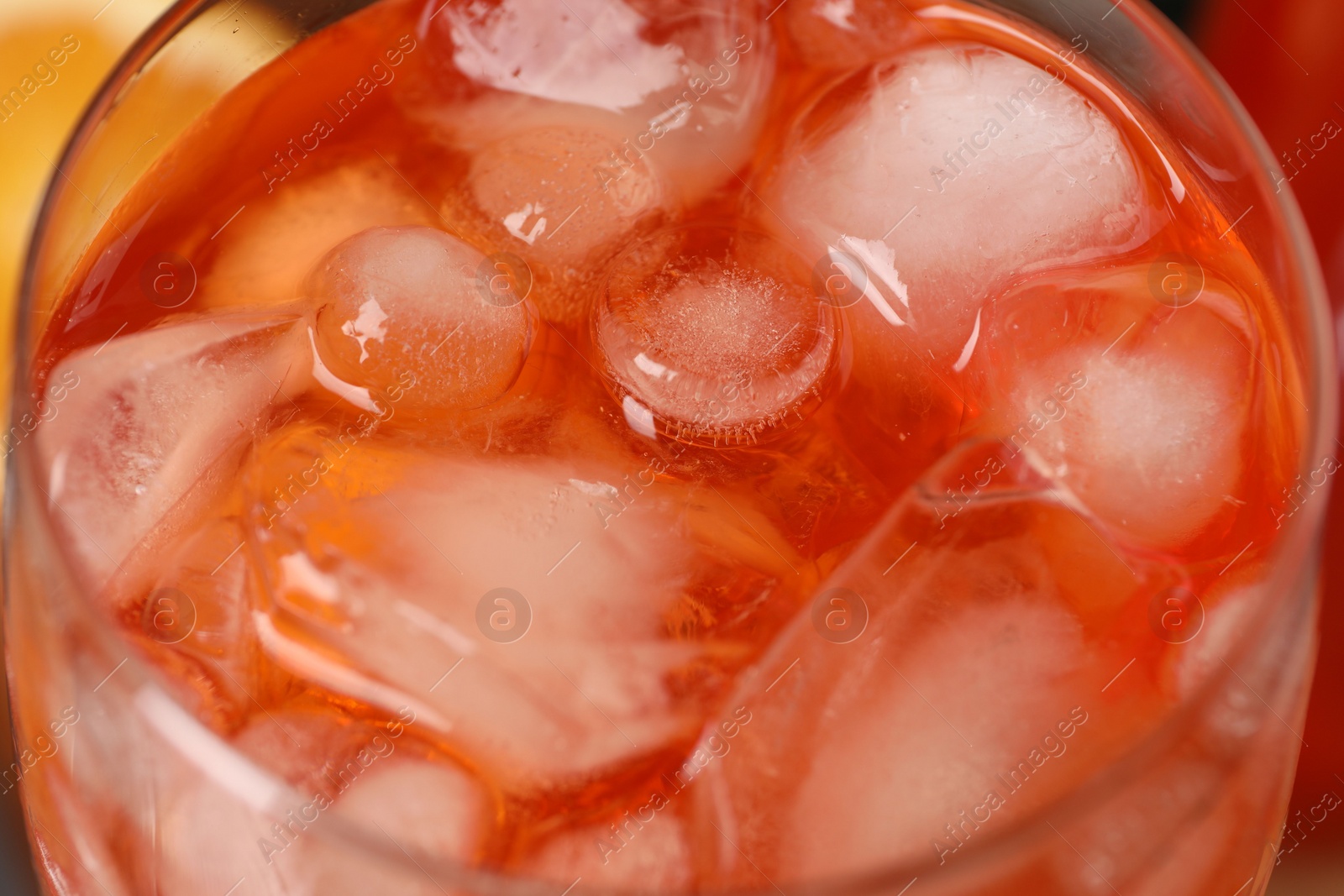 Photo of Aperol spritz cocktail and ice cubes in glass on table, closeup