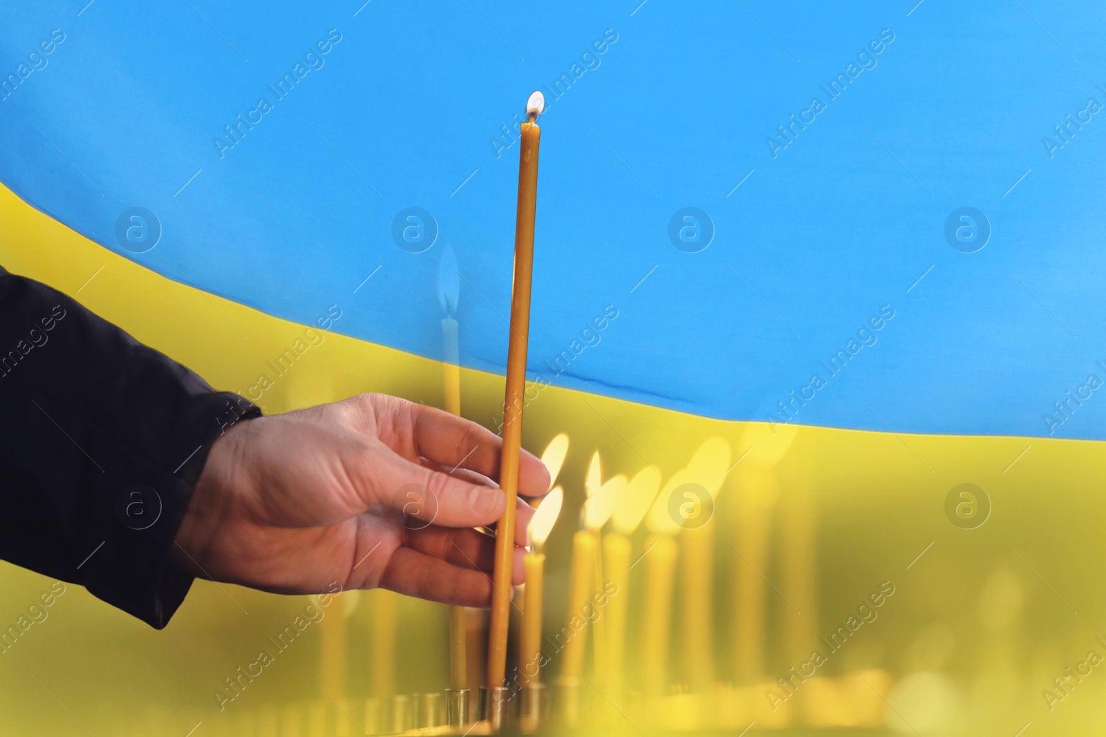 Image of Man with candle against Ukrainian national flag, closeup