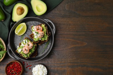 Delicious sandwiches with guacamole, shrimps and black sesame seeds on wooden table, flat lay. Space for text