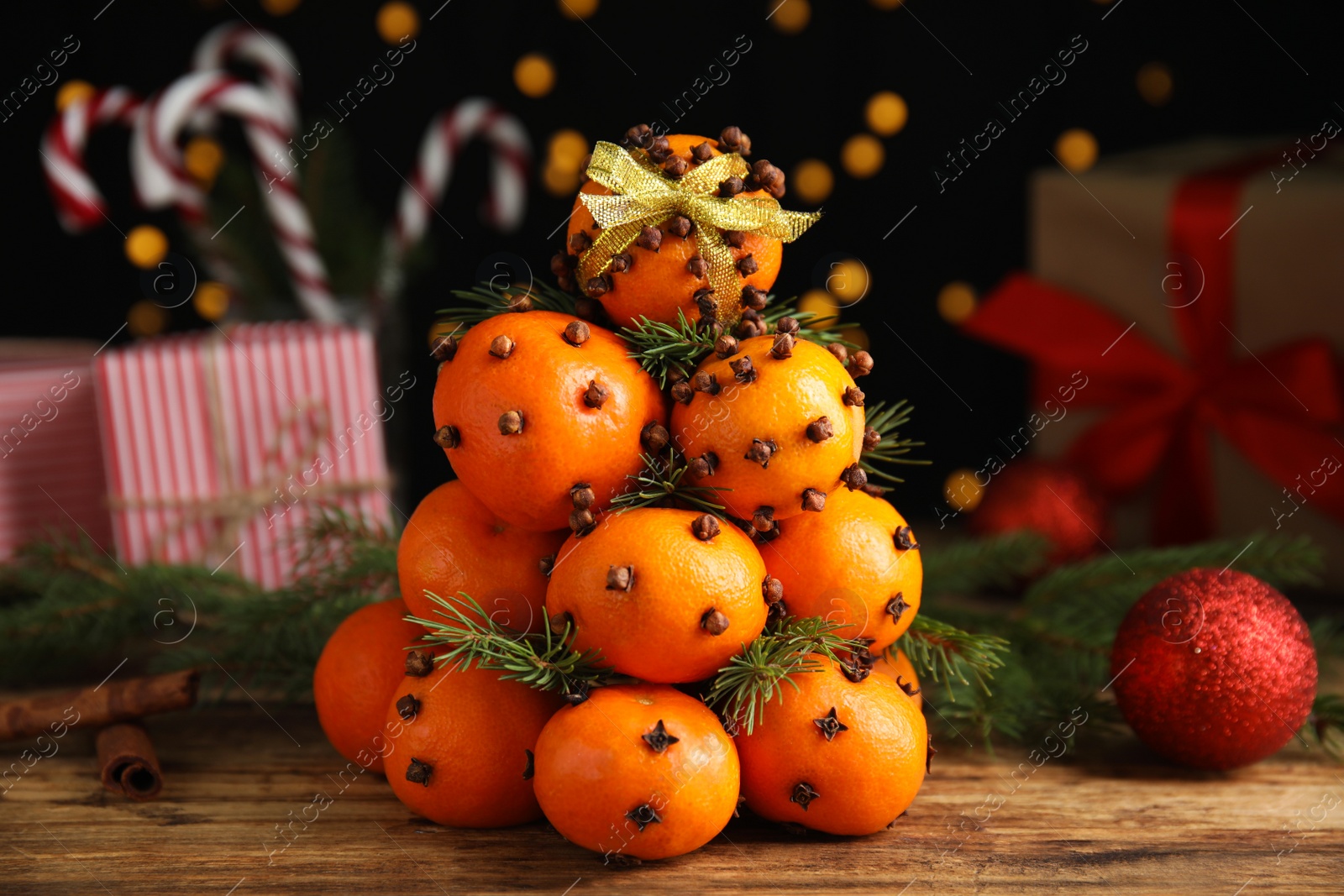 Photo of Pomander balls made of tangerines with cloves and fir branches on wooden table