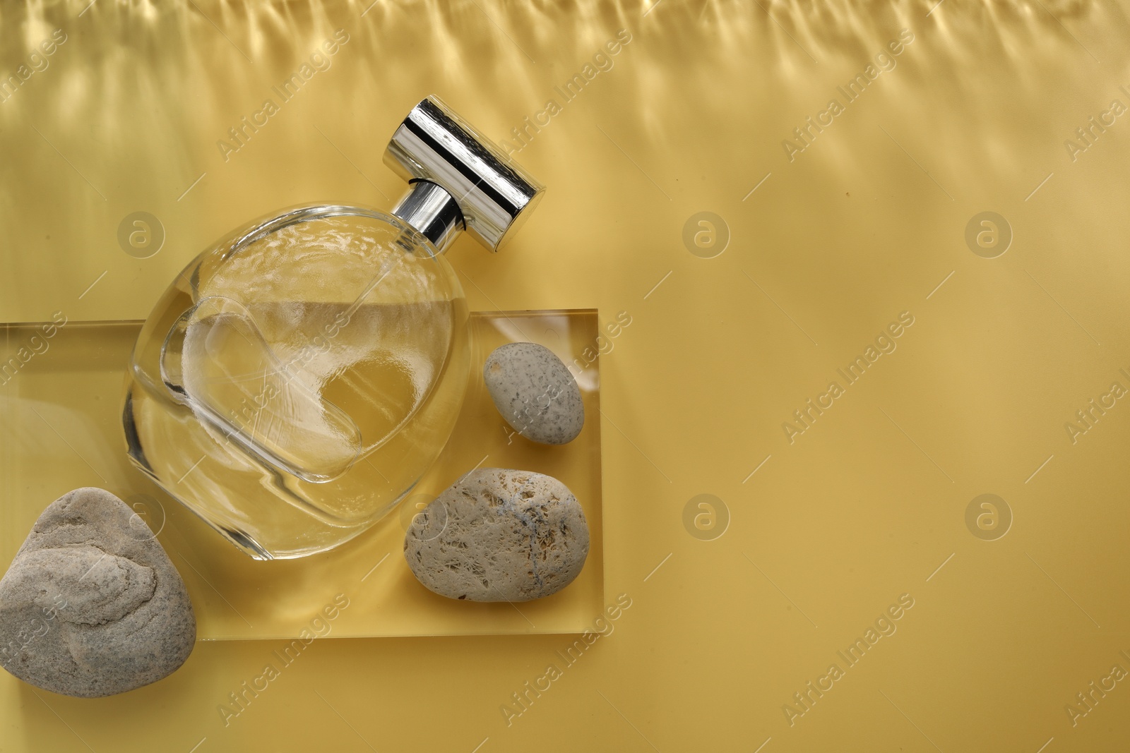 Photo of Stylish presentation of luxury perfume in bottle on golden background, flat lay. Space for text