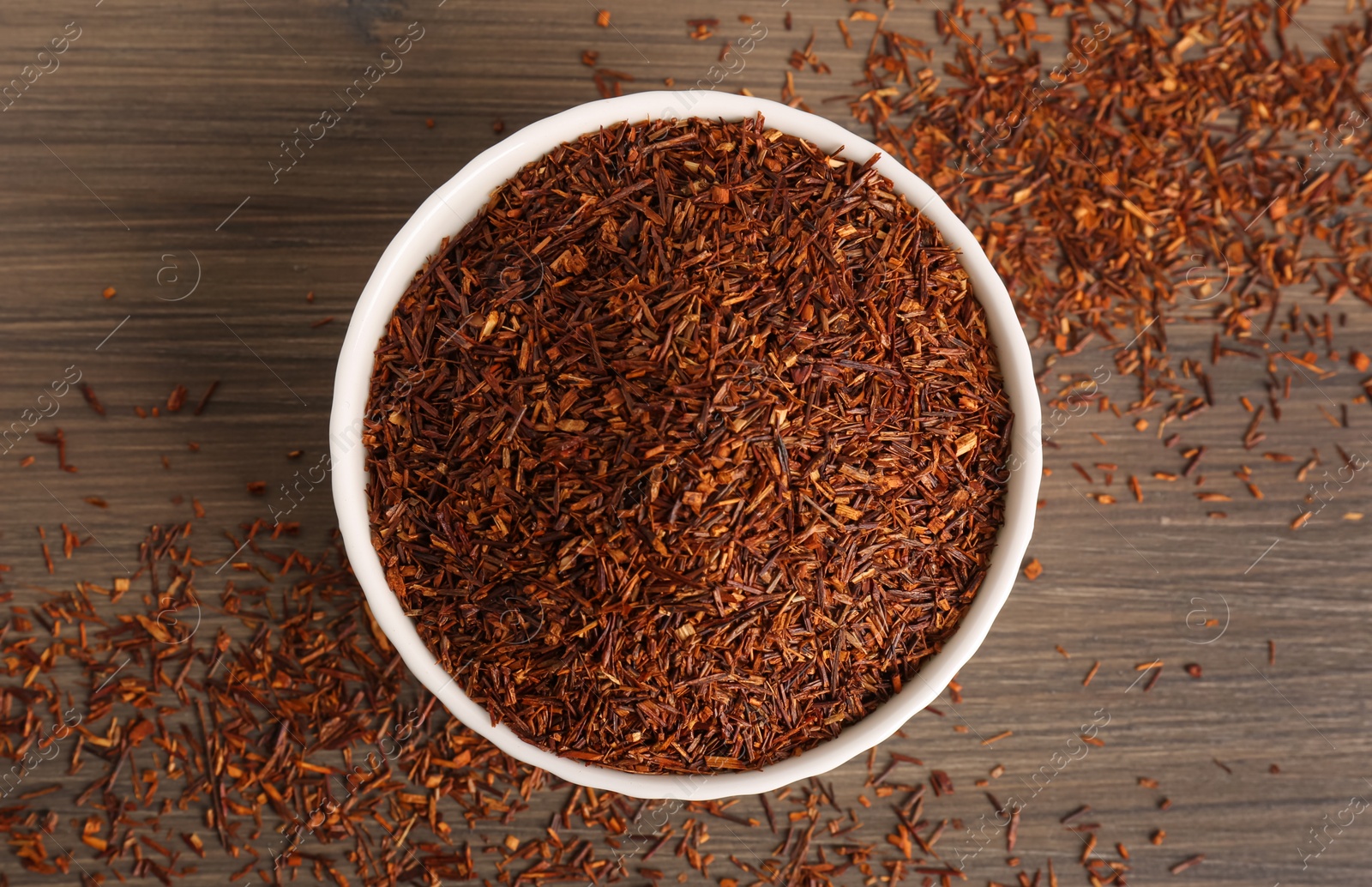 Photo of Dry rooibos leaves on wooden table, flat lay