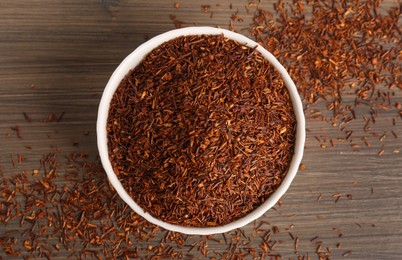 Dry rooibos leaves on wooden table, flat lay