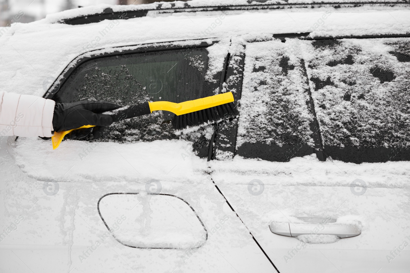 Photo of Man cleaning snow from car outdoors, closeup