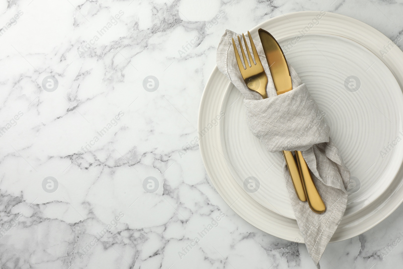 Photo of Stylish setting with cutlery, napkin and plates on white marble table, top view. Space for text