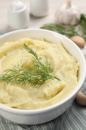 Bowl of tasty mashed potato with garlic and dill on beige wooden table, closeup