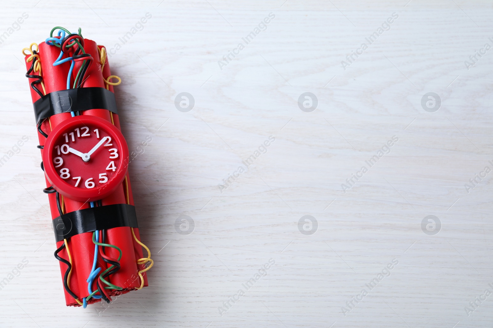 Photo of Explosive dynamite time bomb on white wooden background, top view. Space for text