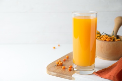 Sea buckthorn juice and fresh berries on white table, closeup. Space for text