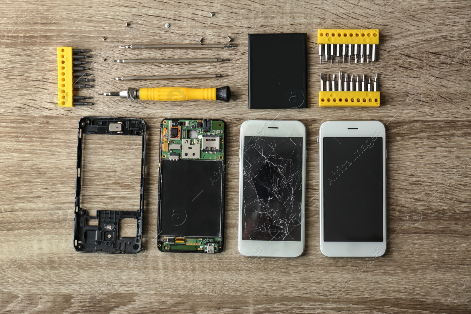 Photo of Flat lay composition with smartphone parts and tools on wooden table. Repairing service