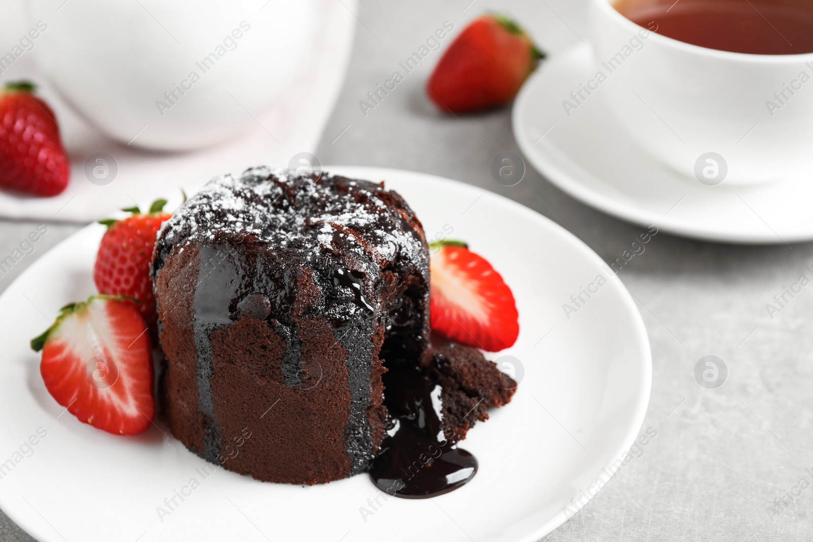 Photo of Delicious warm chocolate lava cake with mint and strawberries on table. Space for text