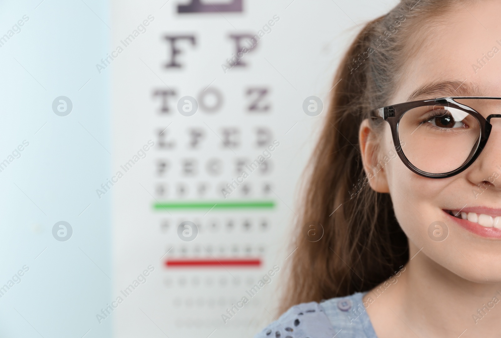 Photo of Cute little girl with eyeglasses in ophthalmologist office. Focus on face
