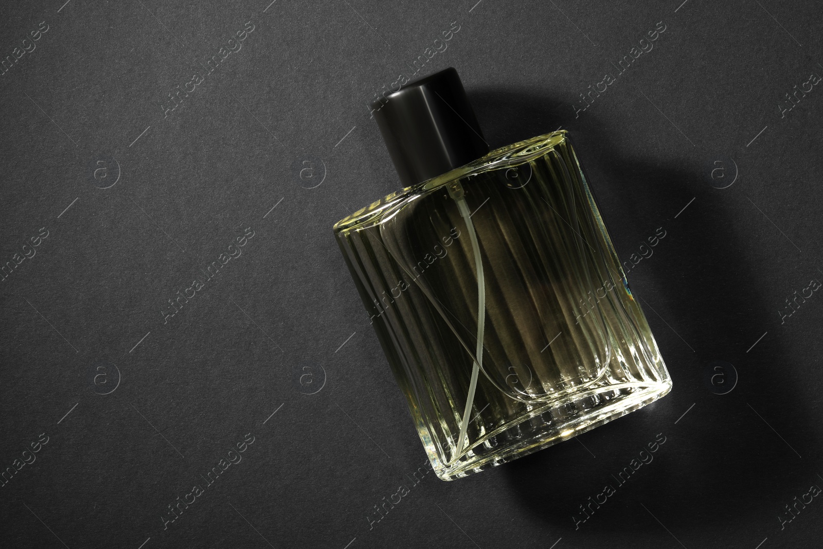 Photo of Luxury men`s perfume in bottle on black background, top view. Space for text