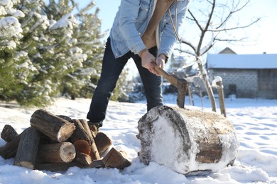 Photo of Man chopping wood with axe outdoors on winter day, closeup