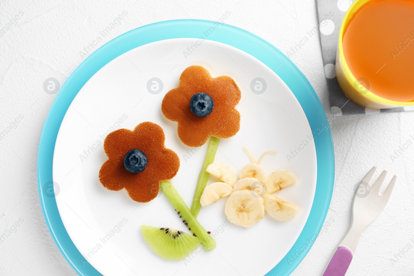 Photo of Tasty pancakes served with blueberries, fruits and juice on white table, flat lay. Creative idea for kids breakfast