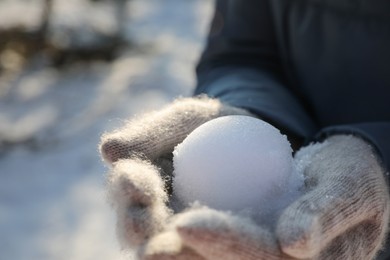 Photo of Woman holding snowball outdoors on winter day, closeup