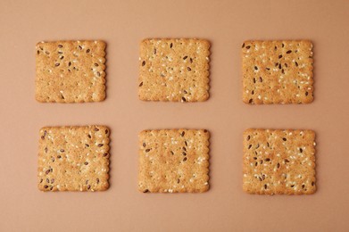 Photo of Cereal crackers with flax and sesame seeds on beige background, top view