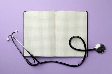 Open notebook and stethoscope on violet background, flat lay. Space for text
