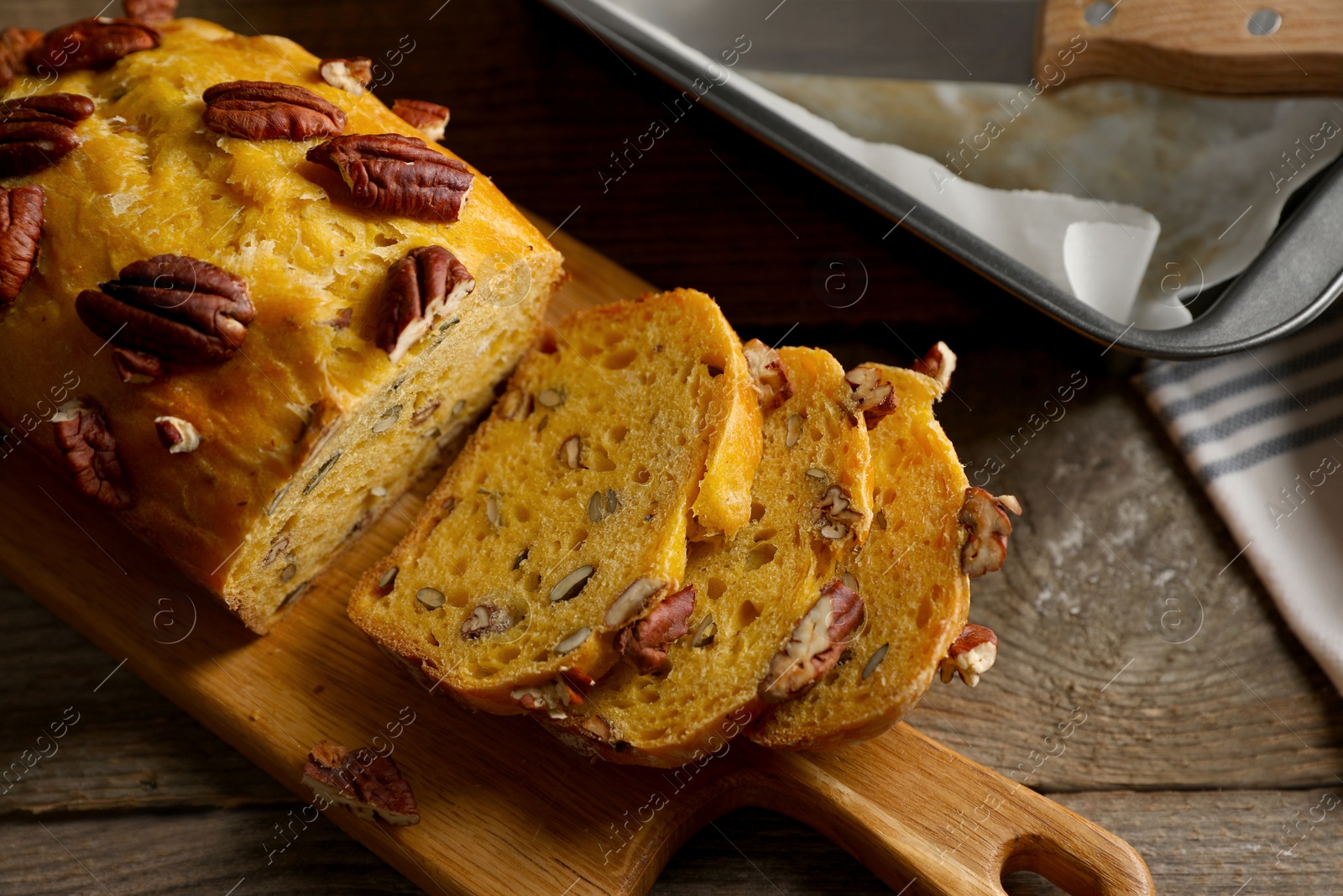 Photo of Cut pumpkin bread with pecan nuts on wooden table, flat lay