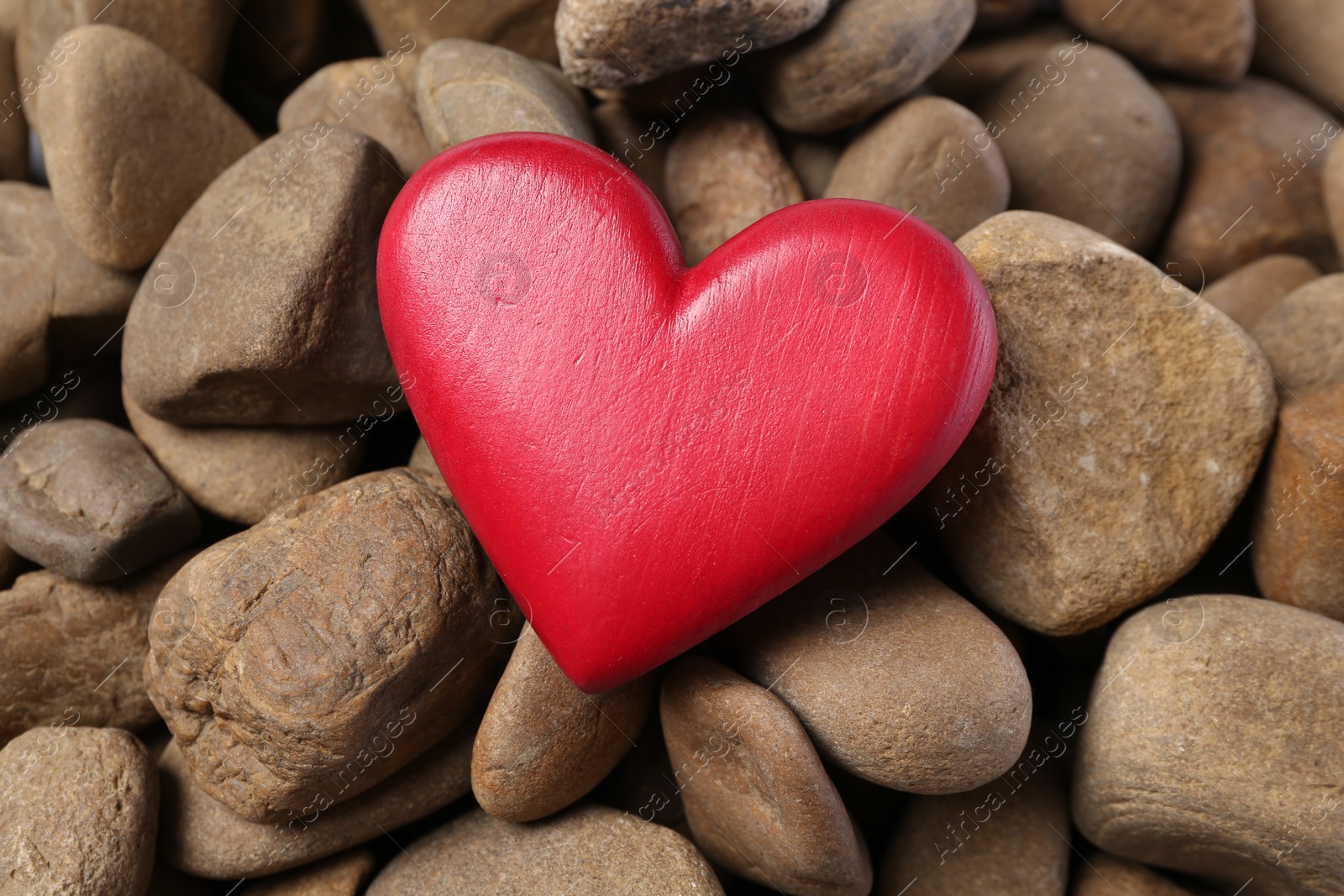 Photo of Red decorative heart on stones, top view