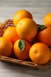 Photo of Many ripe oranges and green leaves on wooden table