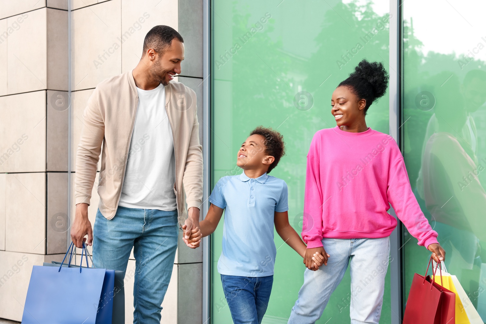 Photo of Family shopping. Happy parents and son with colorful bags near mall outdoors