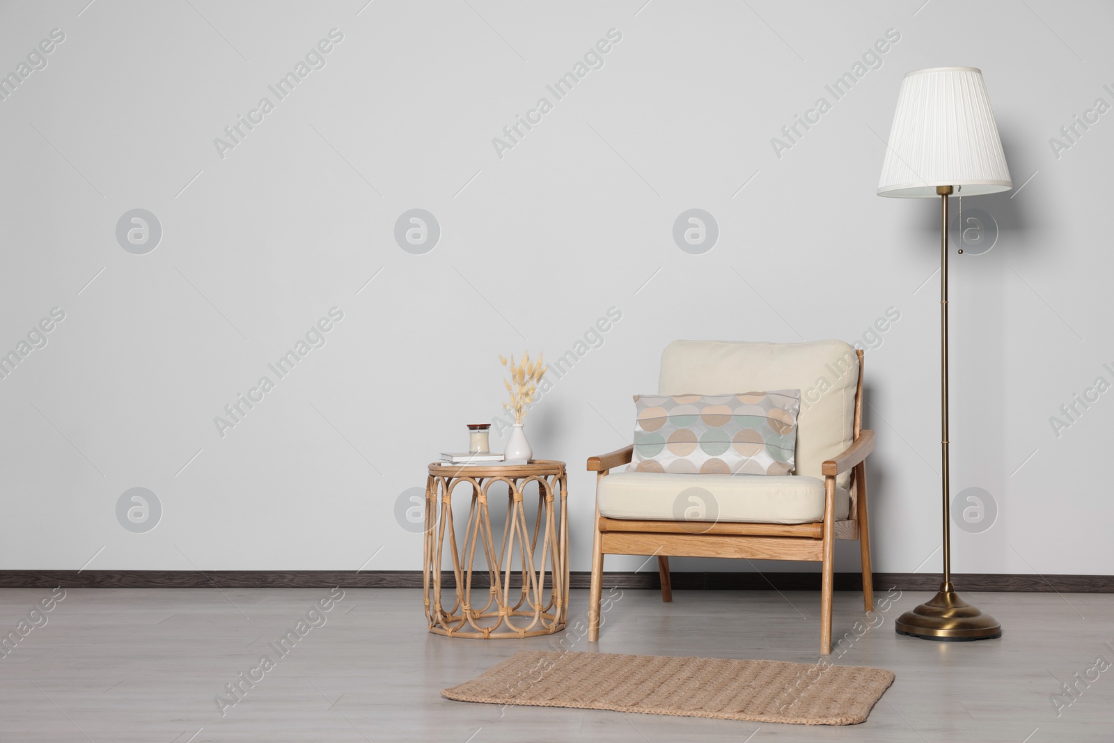 Photo of Stylish armchair, floor lamp and table near white wall, space for text. Interior design