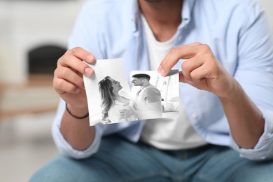 Image of Divorce and breakup. Man ripping photo at home, closeup. Black and white picture symbolizing loss of feelings