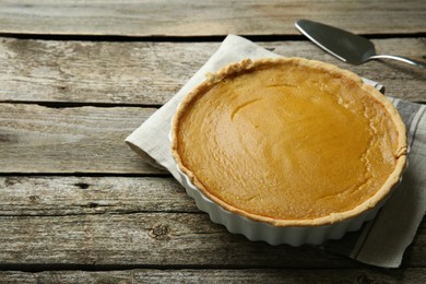 Photo of Delicious pumpkin pie and server on wooden table, space for text