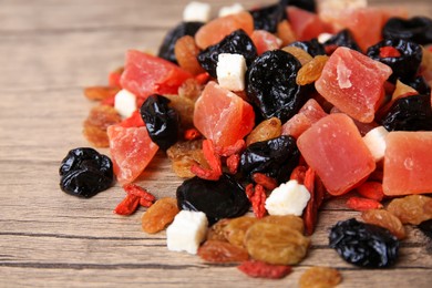 Photo of Pile of different tasty dried fruits on wooden table, closeup