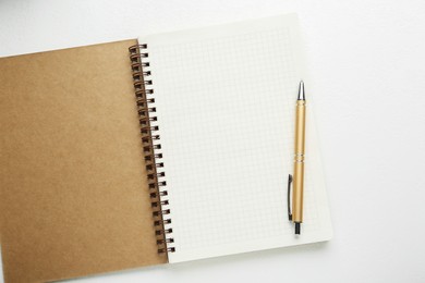 Open notebook and pen on white table, top view. Space for text