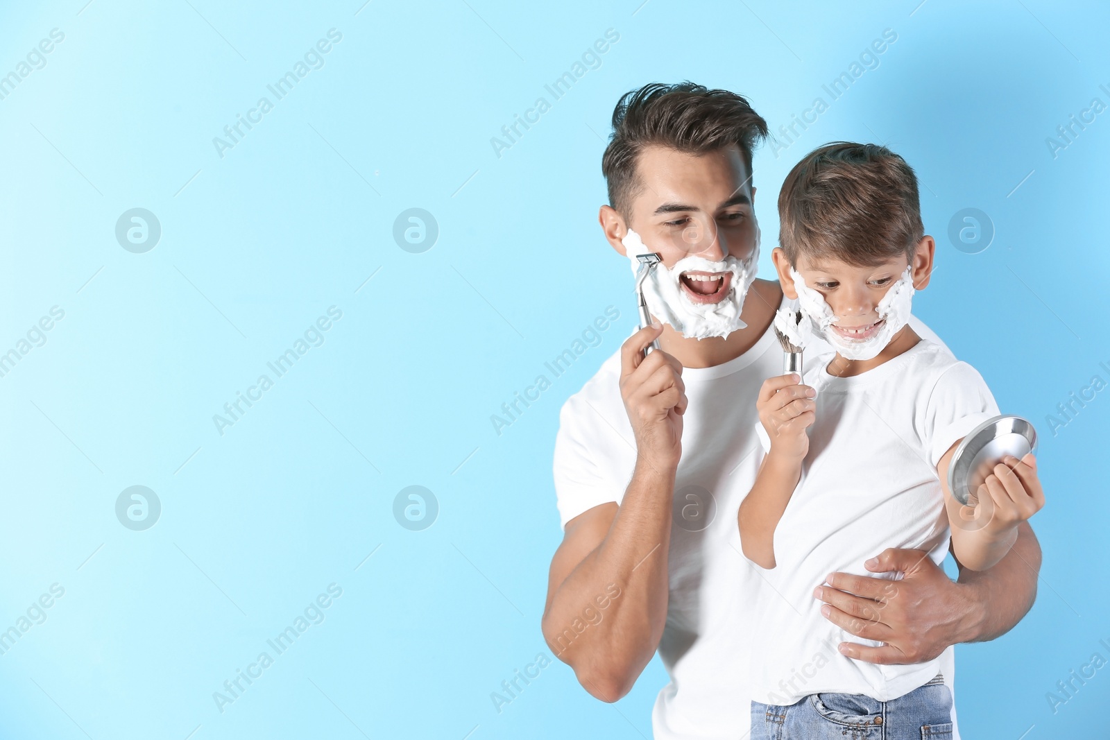 Photo of Father and son shaving on color background. Space for text