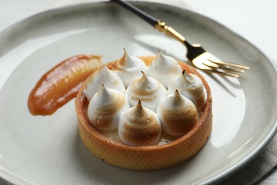 Tartlet with meringue on white plate, closeup. Delicious dessert