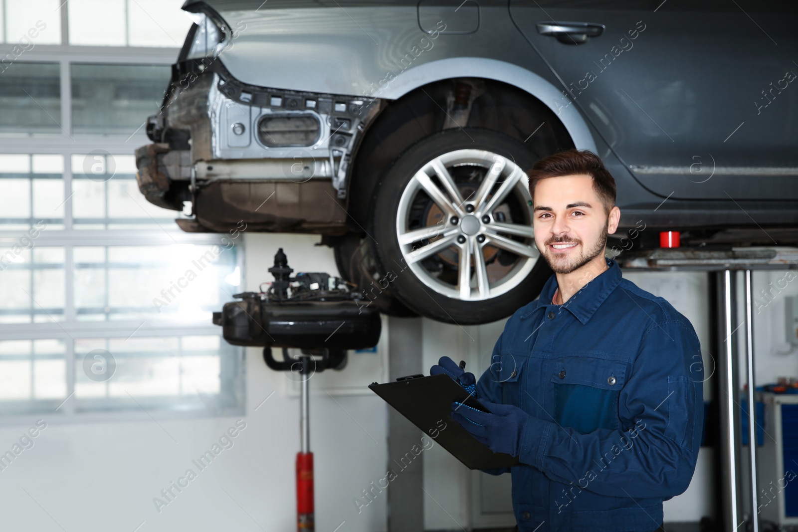 Photo of Technician checking car on hydraulic lift at automobile repair shop