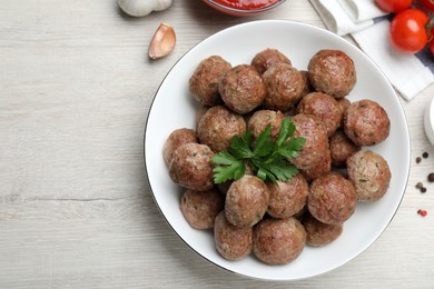 Photo of Tasty cooked meatballs with parsley on white wooden table, flat lay. Space for text