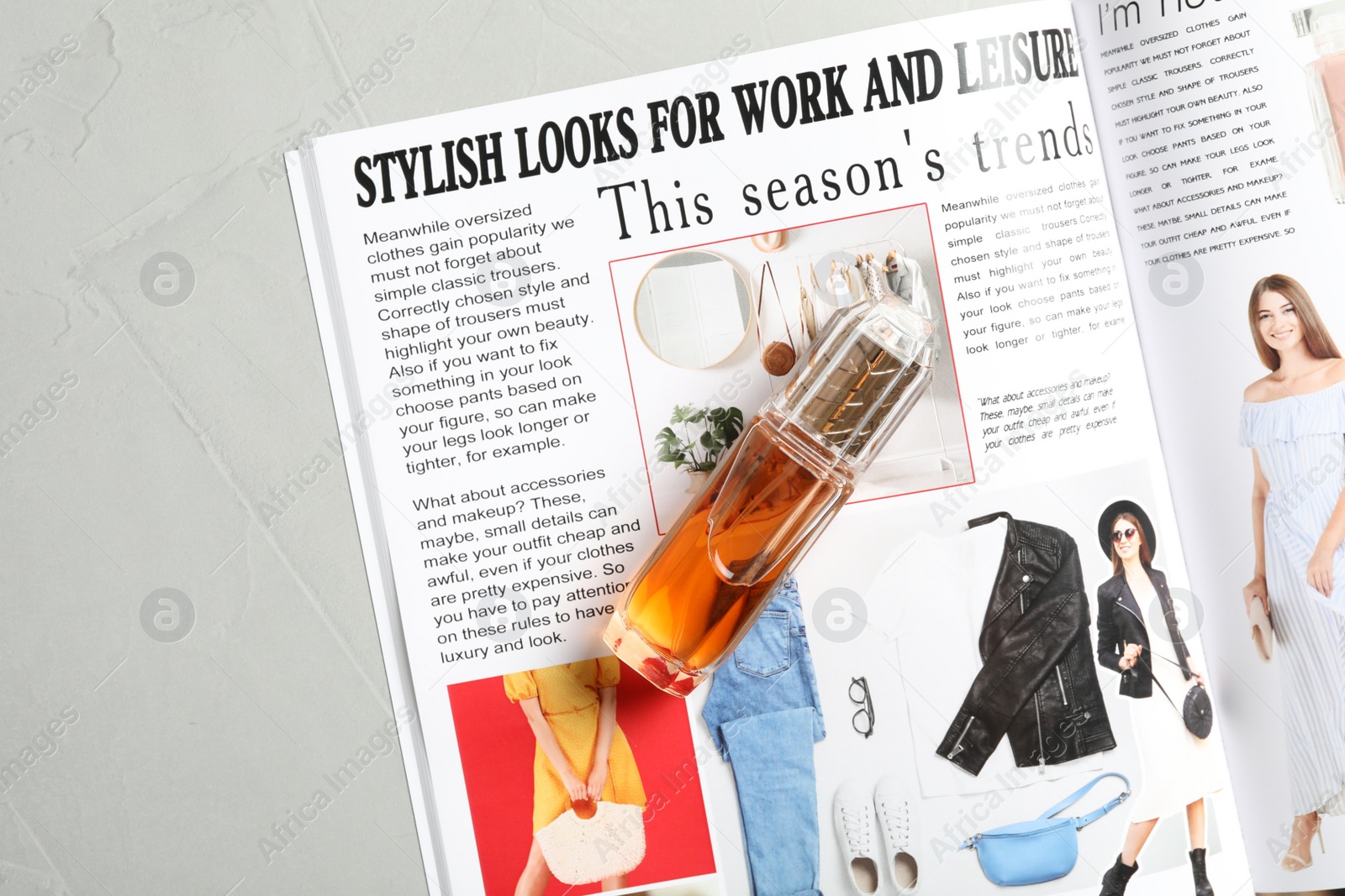 Photo of Open fashion magazine and perfume on grey table, flat lay