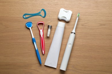 Photo of Flat lay composition with tongue cleaners and teeth care products on wooden table