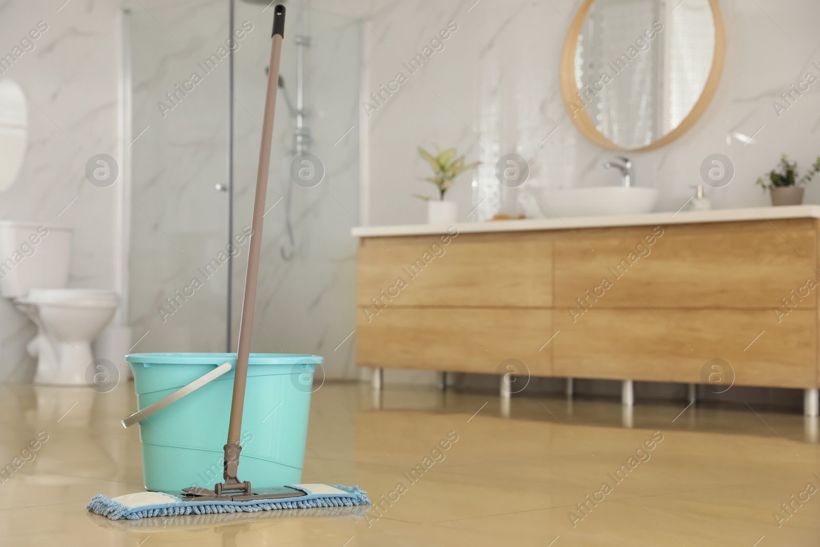 Photo of Bucket and mop on floor at home, space for text. Cleaning equipment