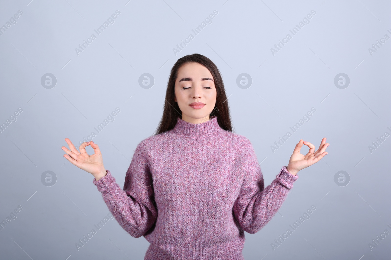 Photo of Young woman meditating on grey background. Stress relief exercise