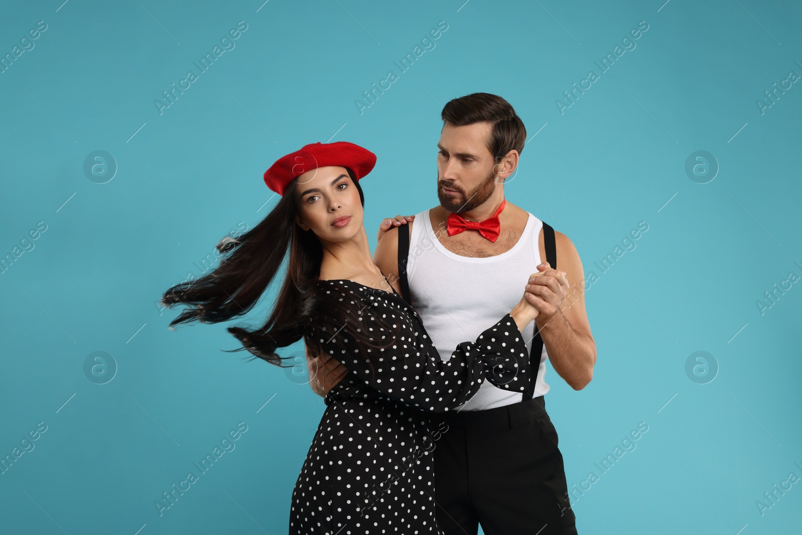 Photo of Beautiful couple dancing together on light blue background