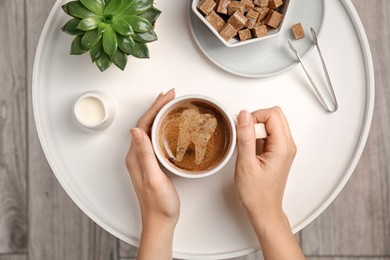 Coffee causing dental problem. Woman with cup of hot drink at table, top view