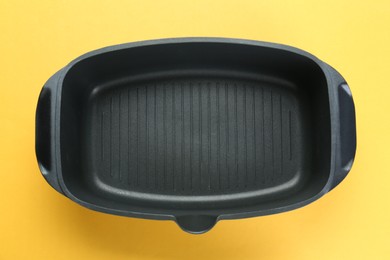 Photo of Black pot on pale orange background, top view