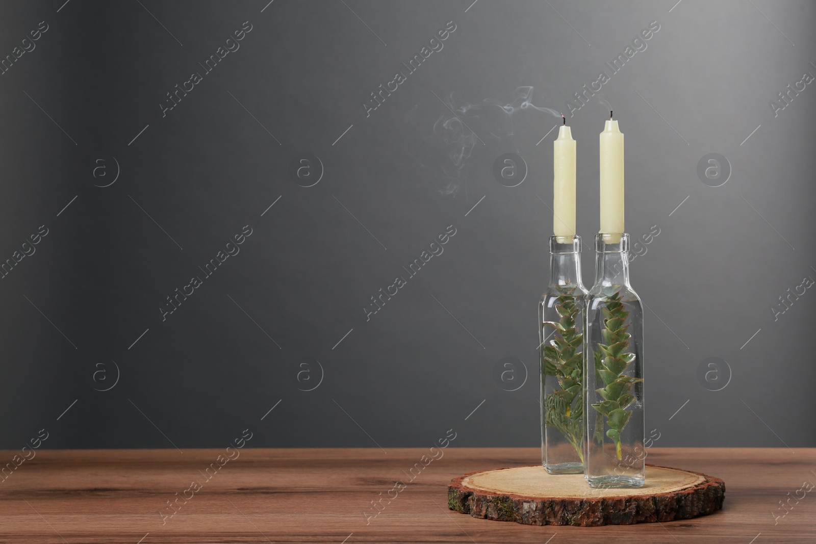 Photo of Candles in stylish glass holders on wooden table Space for text