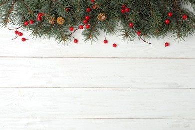 Flat lay composition with fir branches and berries on white wooden background, space for text. Winter holidays